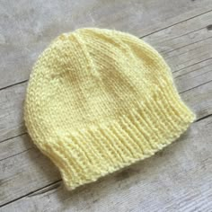 a yellow knitted hat sitting on top of a wooden floor