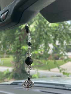 a car dashboard with beads hanging from it's side window and trees in the background