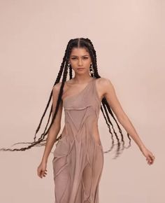 a woman with long braids walking down the runway wearing a dress and sandals on her feet