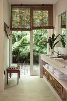 a bathroom with a large window and lots of greenery