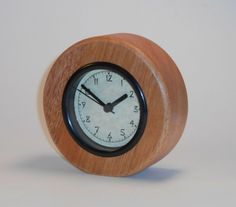 a small wooden clock with roman numerals on the face is shown against a white background