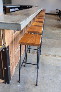 several stools are lined up in front of a bar with an industrial style counter top