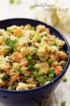 a blue bowl filled with rice and vegetables on top of a white tablecloth next to broccoli