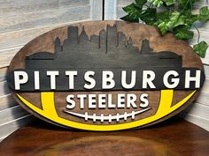 a wooden sign that says pittsburgh steeles on the side of a building with a football in front of it