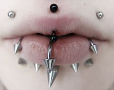 a woman's tongue with metal spikes attached to her lip and nose piercings