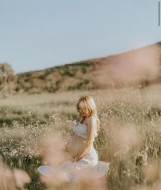 a pregnant woman is sitting in a field