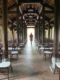 a man is walking down the aisle in an old building with many chairs on it