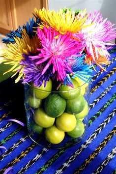 a vase filled with fruit and flowers on top of a table