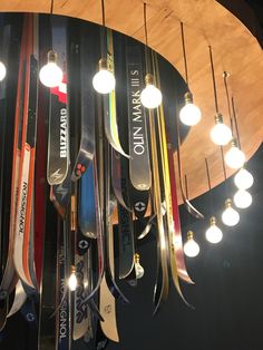 a bunch of skis hanging from the ceiling in a room with lights on it