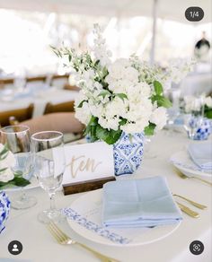 the table is set with blue and white plates, napkins, and flowers in vases