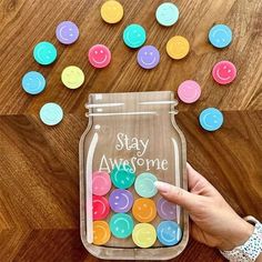 someone is holding up a jar with buttons in it and the words stay awesome written on it