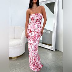 a woman standing in front of a mirror wearing a pink and white floral print dress