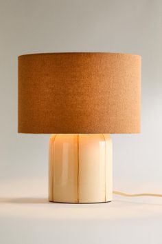 a table lamp with a brown shade on the base and a light bulb plugged in