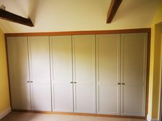 an empty room with white cupboards and yellow walls