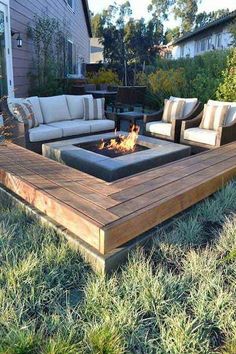 a fire pit in the middle of a yard with couches and chairs around it