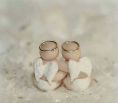 two wedding rings sitting on top of each other in the sand with hearts painted on them