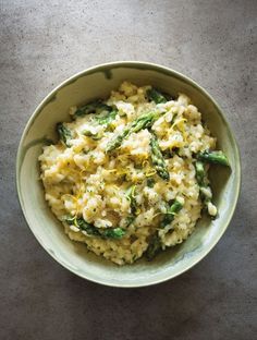 a bowl filled with macaroni and cheese covered in asparagus on top of a table