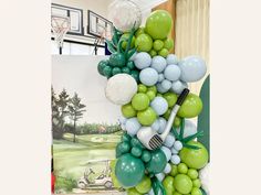 the balloon arch is decorated with green, white and blue balloons that match the golf theme