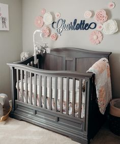 a baby crib in a nursery with pink and white paper flowers on the wall