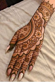 a henna on someones hand that is sitting on a bed