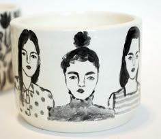 two coffee mugs with black and white designs on them, one has a woman's face painted on it