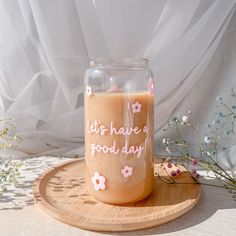 a glass jar with some writing on it sitting on a wooden tray next to flowers