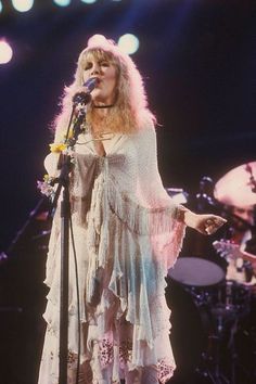 a woman standing in front of a microphone on stage