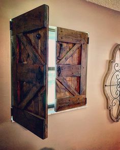 an open wooden door on the side of a wall next to a mirror and window