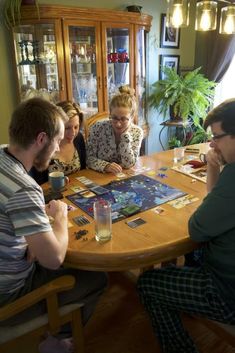 a group of people sitting around a table playing a board game with cups on it