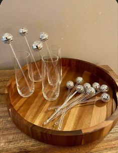 four glasses and five silver balls on a wooden tray