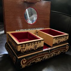 two wooden boxes sitting on top of a black leather couch next to a round mirror