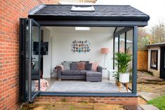 a living room with a couch inside of it next to a brick wall and green grass