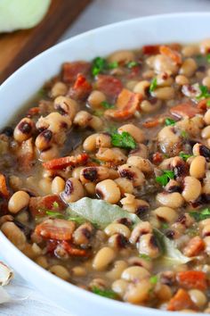 a white bowl filled with beans and carrots on top of a wooden cutting board