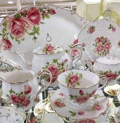 a table topped with lots of white and pink plates covered in flowers on top of each other