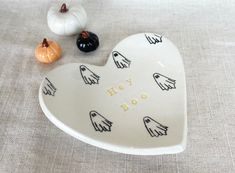 a heart shaped dish with happy booze written on it and two small pumpkins in the background