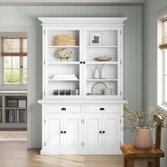 a white china cabinet with glass doors and drawers in the middle of a living room