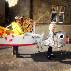 two people dressed in costumes are holding a fake fish and a lifeguard's boat