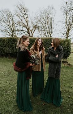 three women in long green dresses are talking to each other