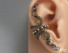 Adjustable steampunk ear cuff, no piercing required! It's made of brass and copper wire, seed beads and recycled vintage brass watch wheels. Oxidized and carefully polished. You can wear it on both the left or right ear. Available: - single - pair You can find more ear cuffs here: https://www.etsy.com/shop/bodaszilvia?section_id=10952870&ref=shopsection_leftnav_2 Plz, read my policies before buying. Thank you! If you are interested in news, work in progress photos or just want to know more about Unique Metal Wire Wrapped Ear Cuff, Unique Adjustable Brass Wrap Earrings, Adjustable Unique Wrap Earrings In Brass, Handmade Copper Ear Cuff With Unique Style, Unique Handmade Copper Ear Cuff, Handmade Unique Copper Ear Cuff, Unique Gold Wire Wrapped Ear Cuff, Gold Metal Wire Wrapped Ear Cuff, Gold Wire Wrapped Ear Cuff