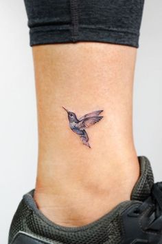 a small tattoo on the ankle of a woman's foot with a hummingbird