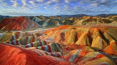 the colorful hills are painted in different colors and sizes, as well as clouds above them