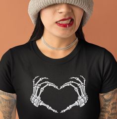 Get ready to rock this Halloween with our Skeleton Hands T-Shirt. This spooky yet stylish tee features detailed skeleton hand prints, giving you an edgy and unique look. Whether you're a fan of Halloween or just want to show off your love for skeleton rock on, this t-shirt is perfect for you. It also makes a great gift for her on Valentine's Day, with its comfortable bleached design made from high-quality materials. Stand out from the crowd and grab this must-have Halloween shirt today! This classic unisex jersey short sleeve tee fits like a well-loved favorite. Soft cotton and quality print make users fall in love with it over and over again. These t-shirts have-ribbed knit collars to bolster shaping. The shoulders are tapered for a better fit over time. Dual side seams hold the garment's Hand Prints, Halloween Tshirt, Skeleton Shirt, Skeleton Hand, Tshirt Funny, Skeleton Hands, Rock On, Funny Halloween, Halloween Funny