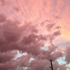 the sky is filled with pink clouds and power lines