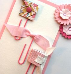 some paper flowers are laying on top of a piece of white paper with pink ribbon