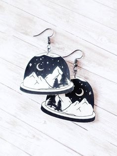 "How cute are these mountainous snowglobe earrings?! They are cut from white faux leather and have black iron-on vinyl for the \"liquid\" in the globe. The moon and stars are iron-on silver foil and the ear wires are gunmetal. Earrings measure 2.5\" from the very tip top of the earring wire, which is HYPOALLERGENIC (nickel & lead free). All earrings are handmade so slight variations may occur with each pair. For hygienic reasons, all earring sales are final but contact me if you have any issues." Snowglobe Earrings, Landscape Earrings, Winter Snow Globe, Gunmetal Earrings, The Moon And Stars, Earring Wire, Faux Leather Earrings, Black Sparkle, Iron On Vinyl