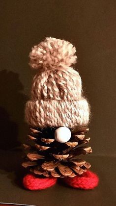 a knitted pine cone with a white ball on top and red shoes underneath it