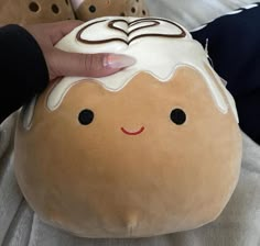 a person holding onto a stuffed toy that looks like a donut with chocolate frosting on it