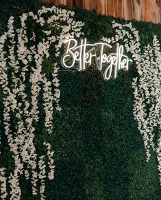 a green wall with white flowers and the words better together written on it's side