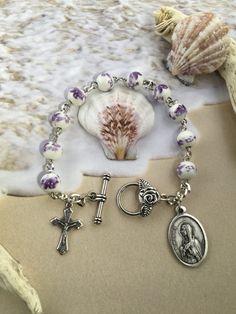 This beautiful saint Monica rosary bracelet has so much durability yet simple and elegant. This particular mini rosary is made with stainless steel wire and chain and ceramic beads. Each bead is adorned with beautiful purple roses. It features a rose toggle clasp for ease of use, and a saint Monica medal.  This would be the perfect confirmation gift, anniversary gift or birthday gift. Materials used: ~Ceramic 8mm beads ~ Saint Monica Medal ~ Stainless Steel chain ~ Stainless Steel wire ~ 3\4 inch crucifix ~ Rose Toggle Clasp  Sizing: Child~ Please specify age of child  Extra Small XS ~ fits 6.5 inches = small woman's wrist. Small S ~ fits 7 inches = average woman's wrist. Medium M ~ fits 8 inches = average man's wrist or woman with large wrist. Large L ~ fits 9 inches = for man with large Saint Monica, Catholic Icons, Bracelet Rosary, St Monica, Mini Rosaries, Mini Bracelet, Rose Violette, Godmother Gifts, Rosary Bracelet