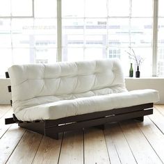 a white couch sitting on top of a hard wood floor next to a large window